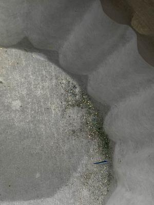 image of filter paper with shiny gold flecks and some green fibers